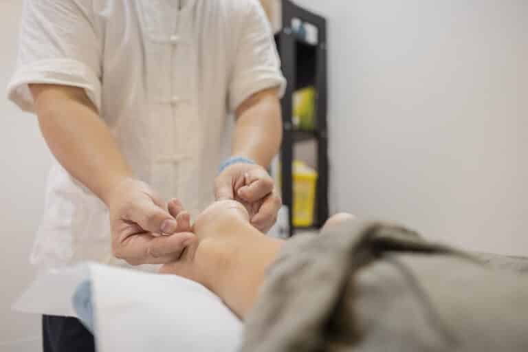 Acupuncturist performing traditional chinese medicine treatment, gently inserting needles into a patient's foot to stimulate energy points and promote health and well being